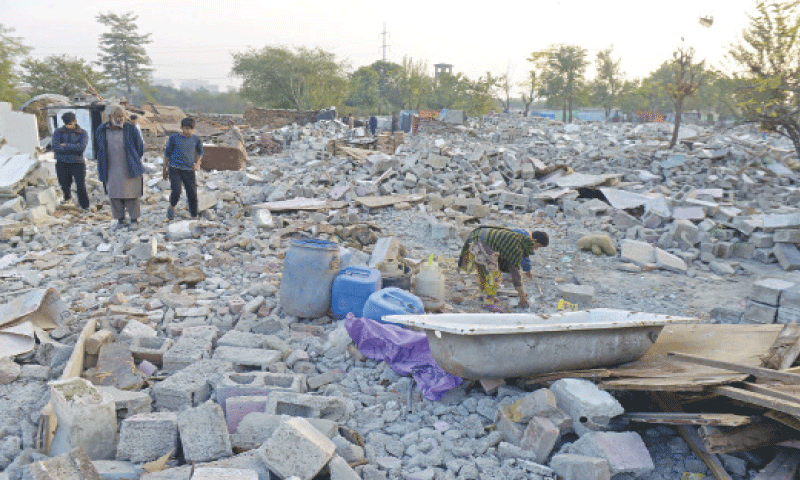Residents of Muslim Colony walk through the debris of houses which were razed during an anti-encroachment operation conducted by CDA in Islamabad on Monday. &mdash; Photo by Mohammad Asim