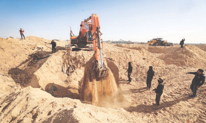 GUNMEN guard an earth mover searching for bodies in Nuseirat refugee camp.&mdash;AFP