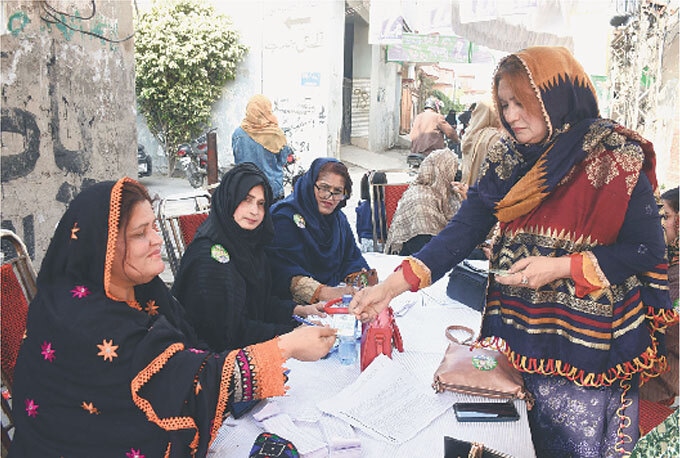 A woman receives her voter number from polling agents.—Online