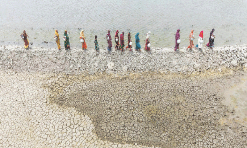 WOMEN carrying pots walk along the parched shores of a river to fetch drinking water at Parshemari village, in Bangladesh&rsquo;s Khulna district.&mdash;AFP