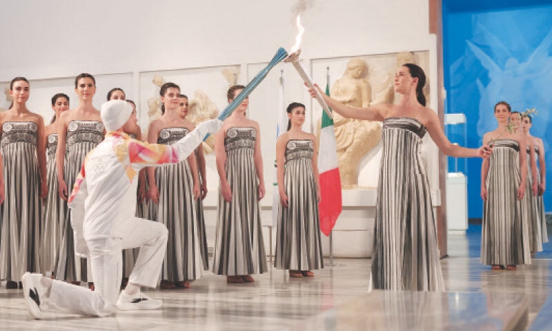 GREEK actress Mary Mina, playing the role of High Priestess, passes the flame to the first torchbearer Petros Gaidatzis during the 2026 Milano-Cortina Winter Olympics flame lighting ceremony on Wednesday.&mdash;Reuters
