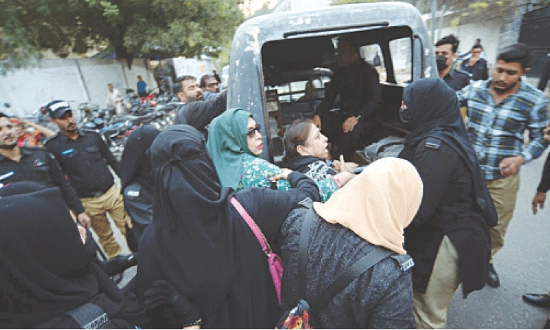 Police bundle PTI workers into a mobile van as they try to stage a protest outside the Karachi Press Club.&mdash;PPI