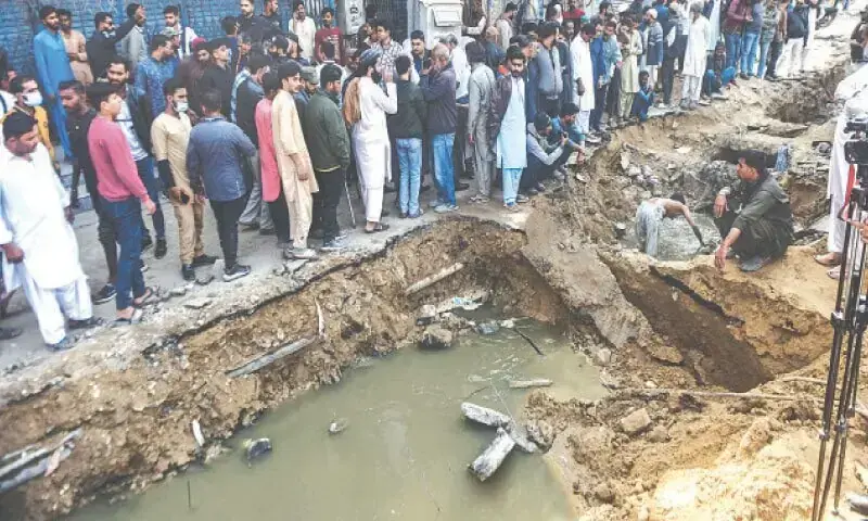 In this file photo, people anxiously wait during the search operation on December 1 to locate a three-year-old child who drowned in a manhole in Gulshan-i-Iqbal. — Fahim Siddiqi / White Star