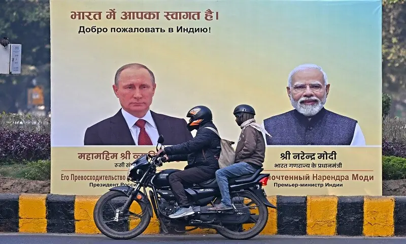 Commuters move past a hoarding with portraits of Russia&rsquo;s President Vladimir Putin (L) and India&rsquo;s Prime Minister Narendra Modi in New Delhi on December 4, 2025. &mdash;AFP