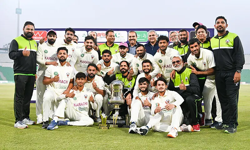 Karachi Blues players and support staff celebrate with the Quaid-e-Azam Trophy after beating Sialkot in the final at the Gaddafi Stadium on December 5, 2025.&mdash;Courtesy PCB