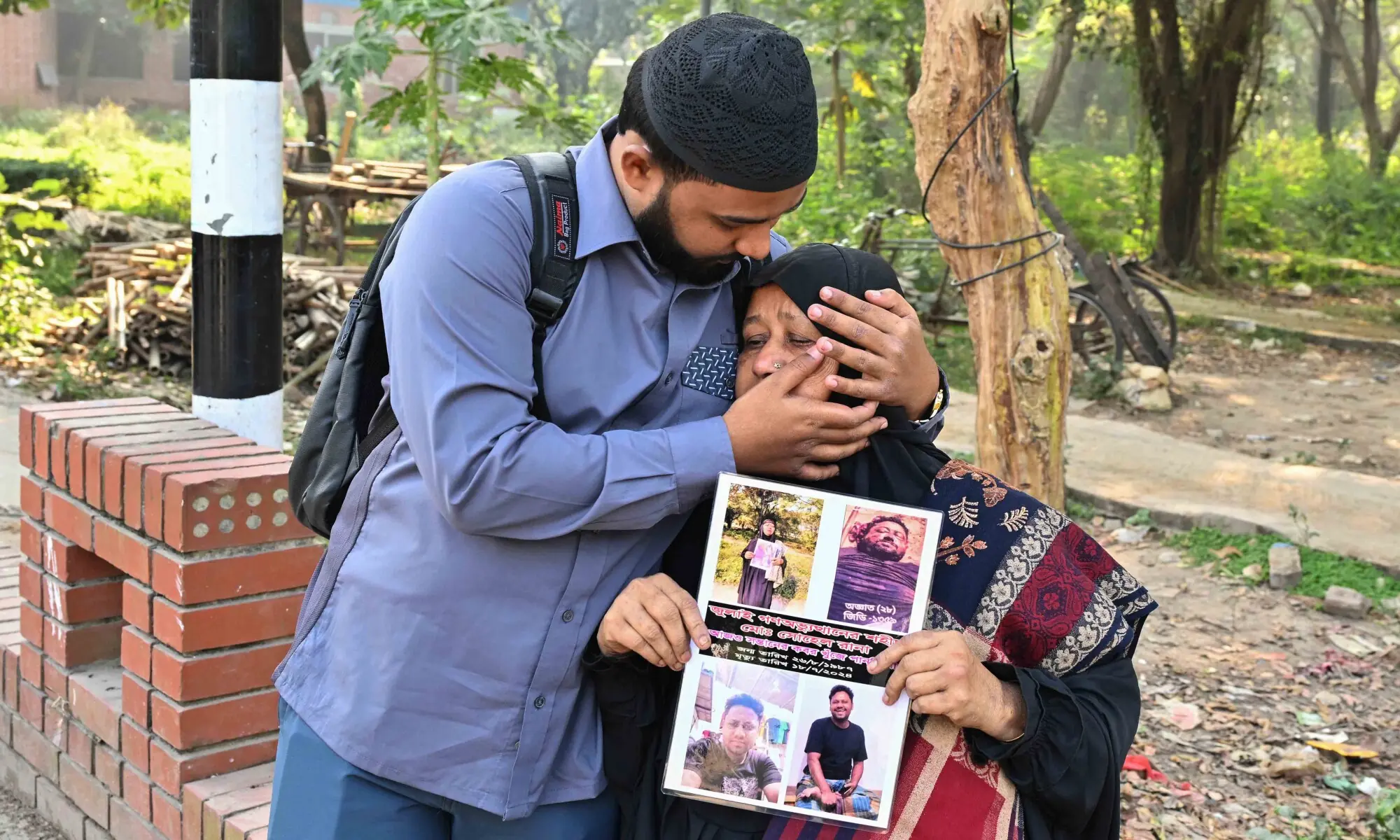 Family members of a missing person react as they stand outside the Martyred Intellectuals Memorial on Sunday. &mdash; AFP