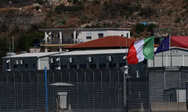 An Italian and a European Union flag flutter at a reception camp set up as part of an Italian government plan to process migrants rescued at sea, in Shengjin, Albania on July 31, 2025. &mdash; Reuters/File