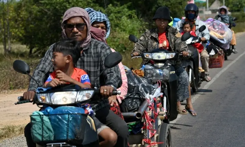 Residents ride their motorbikes along a street after they evacuated following clashes along the Cambodia-Thailand border, in Siem Reap province on December 9. &mdash; AFP