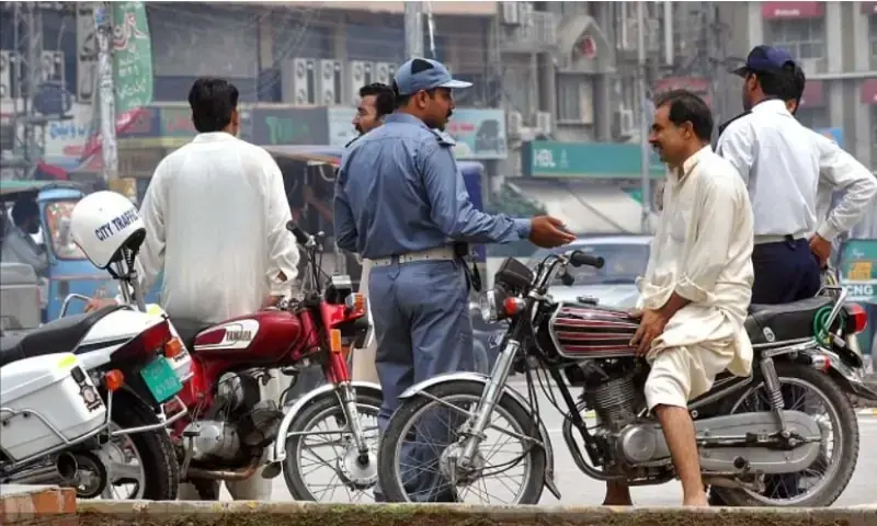 A traffic police official fines a motorcyclist in Punjab. &mdash; Photo couretsy Traffic Police Punjab website/File
