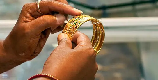 This file photo shows a person holding gold bangles. &mdash; AFP/File