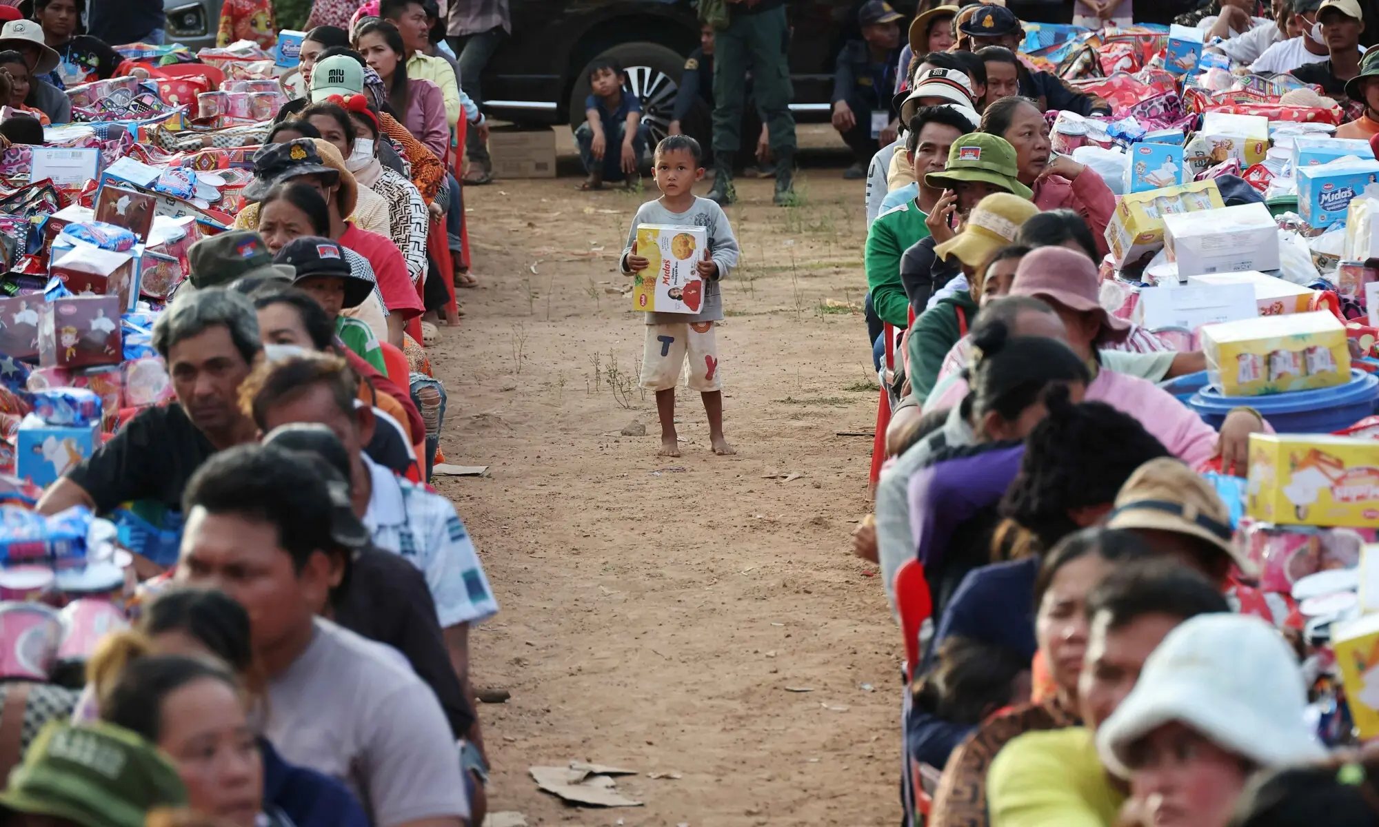 A boy holding a supply box stands among people waiting to collect supplies at Batthkav refugee camp in Cambodia.&mdash;Reuters