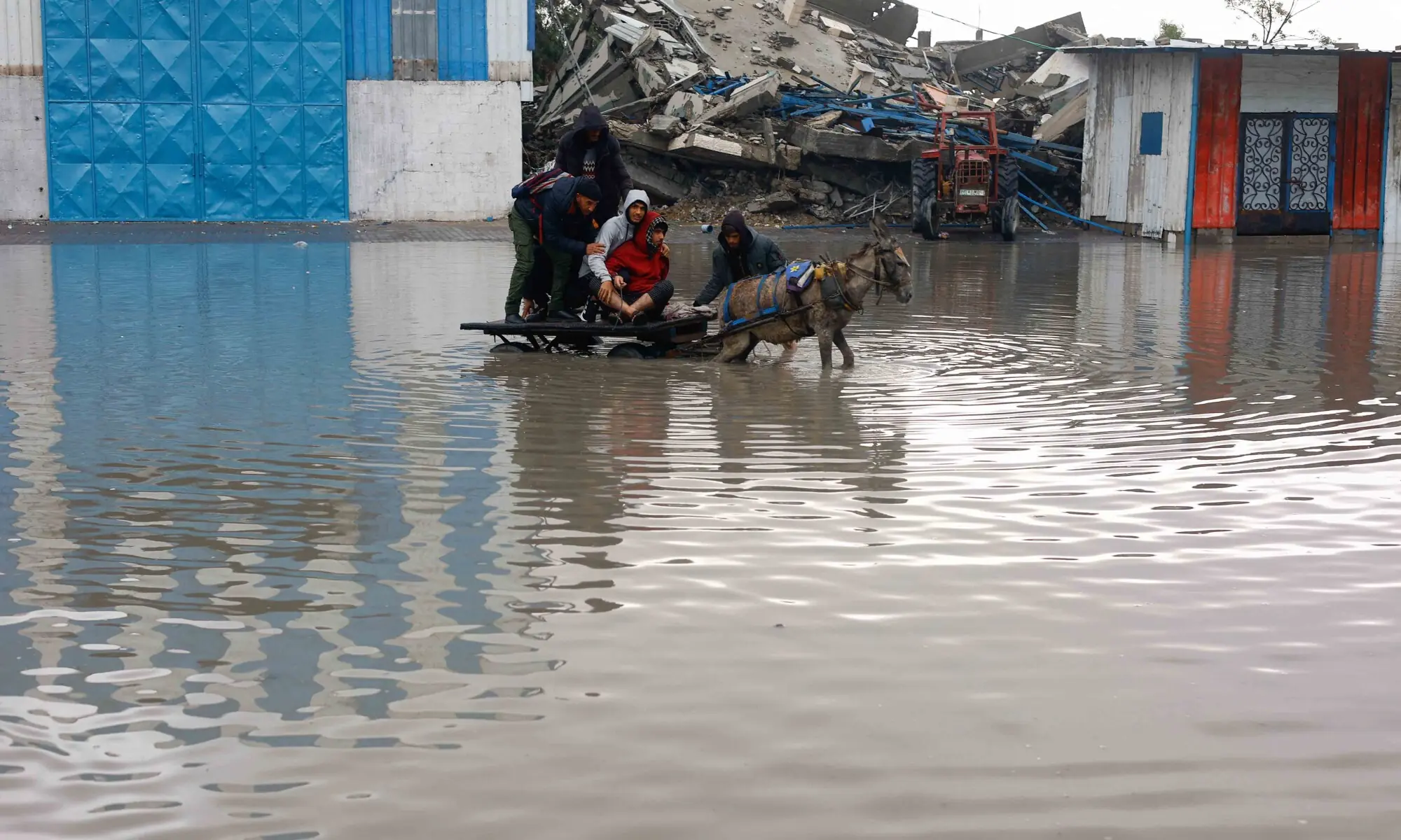 Displaced Palestinians ride a donkey-drawn cart on a rain-flooded street in Gaza City, December 12, 2025. &mdash; Reuters