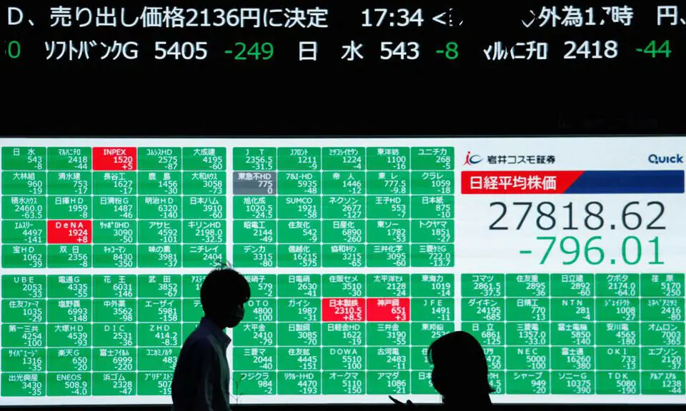People walk past an electric board showing Japan&rsquo;s Nikkei share average in Tokyo, Japan. &mdash; Reuters/File