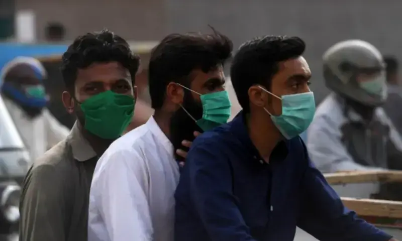 People wearing face masks, sitting on a bike in Pakistan &mdash; AFP/File