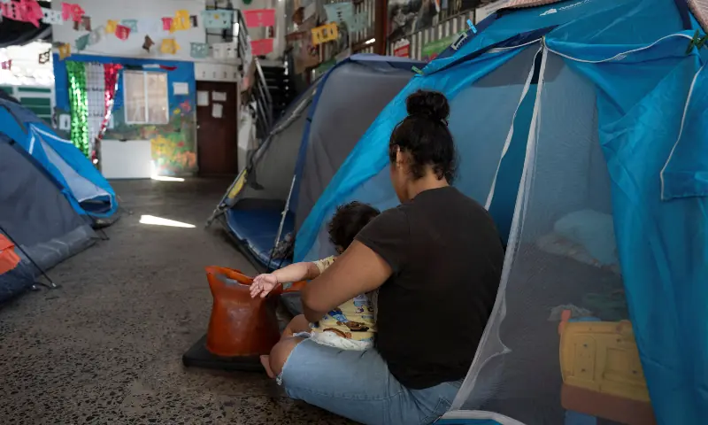 A Mexican migrant and her baby from Morelos sit outside a tent at the Juventud 2000 shelter, where they are staying as they wait to cross into the US, in Tijuana, Mexico on October 31, 2025. &mdash; Reuters