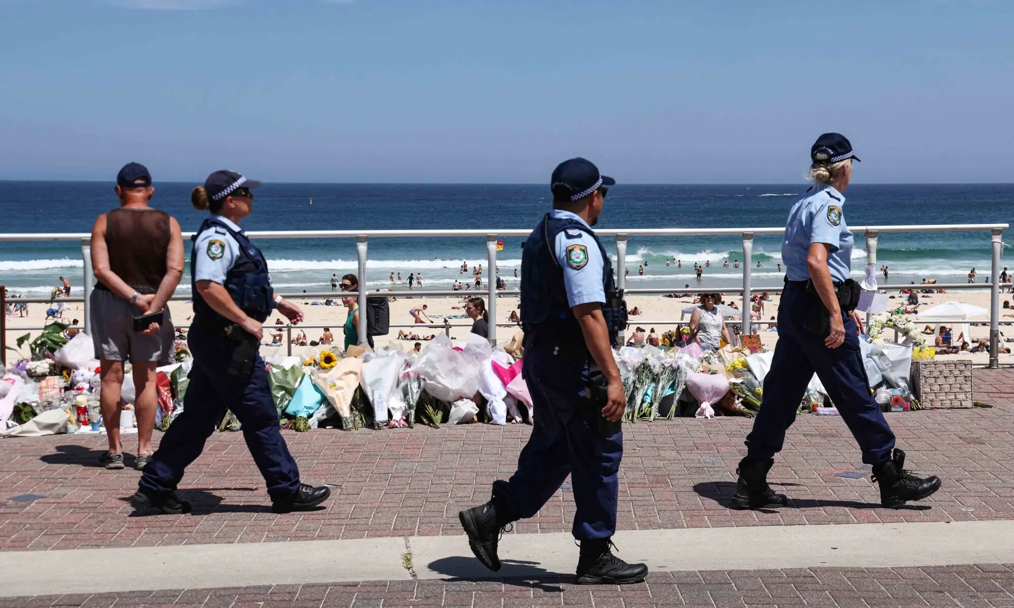 The Police walk past floral tributes left at the promenade of Bondi Beach in Sydney on December 18, 2025, to honour victims of the shooting that took place there on December 14. &mdash; AFP