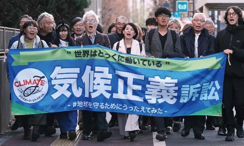 Plaintiffs and their lawyers walk along the sidewalk in front of the Tokyo District Court to appeal that they have filed a lawsuit against the government seeking damages for the government&rsquo;s failure to take action on climate change in Tokyo on December 18, 2025. &mdash; AFP