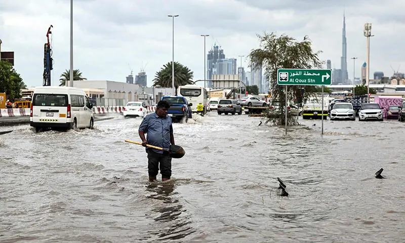 A man wades through flood waters to clear a drain as a street near the Burj Khalifa floods following heavy rains in Dubai, the UAE on December 19. — AFP A man wades through flood waters to clear a drain as a street near the Burj Khalifa floods following heavy rains in Dubai, the UAE on December 19. — AFP