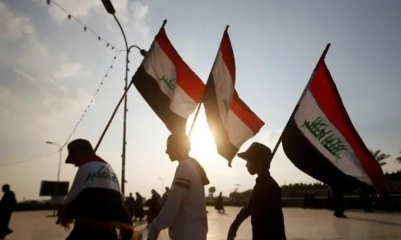 In this file photo, Demonstrators carry Iraqi flags during continuing anti-government protests in Basra, Iraq. &mdash; Reuters