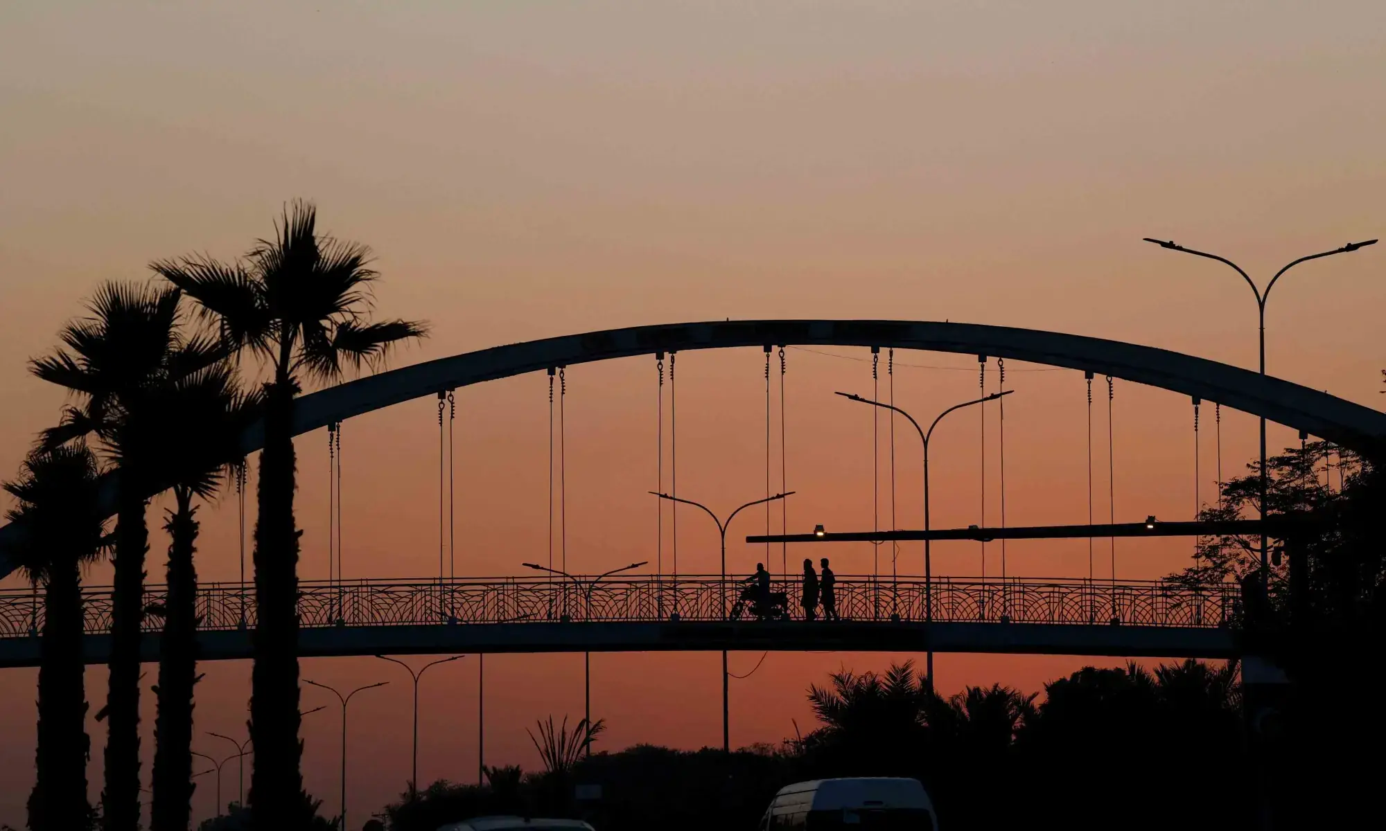 People are silhouetted as they cross a pedestrian bridge during sunset hours, in Islamabad on November 12, 2025. &mdash; Reuters