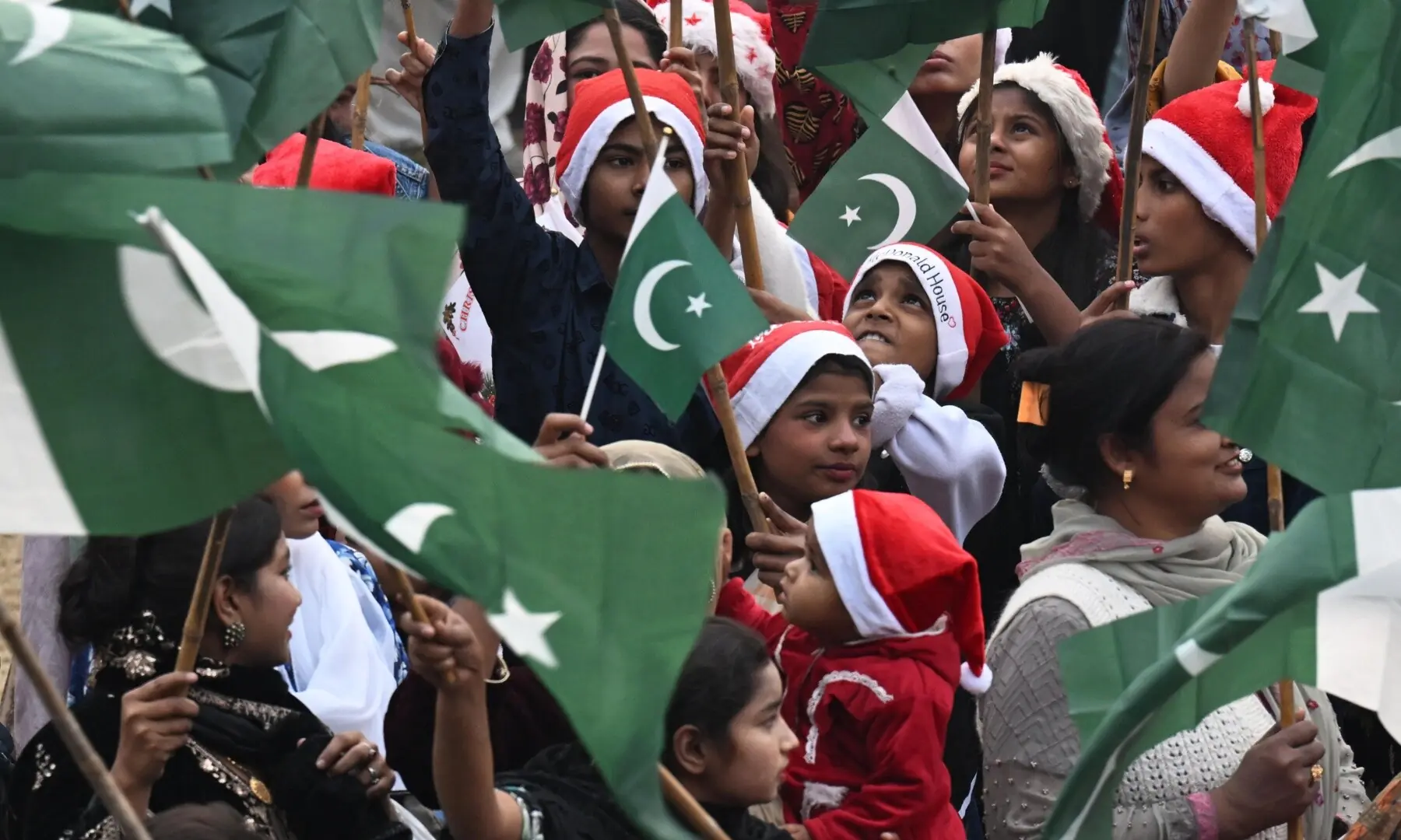 Participants dressed in Santa costumes and holding the Pakistani flag at a Christian peace rally at Sacred Heart Church in Lahore. &mdash; Arif Ali/White Star