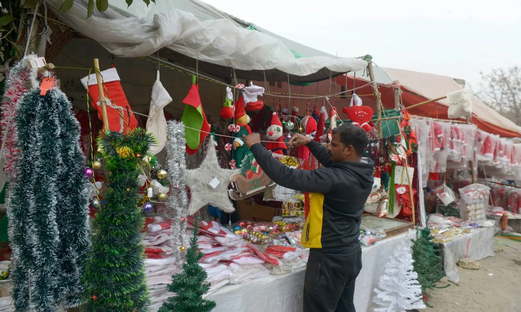 A man arranges various Christmas-related items on a stall along a road in Islamabad&rsquo;s G-7 sector. &mdash; Mohammad Asim/White Star