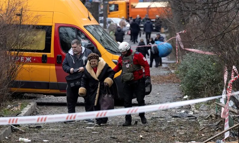 A medic assists a resident as she leaves her apartment building that was hit by a Russian drone, amid Russia&rsquo;s attack on Ukraine, in Kyiv, Ukraine December 23, 2025. &mdash;Reuters