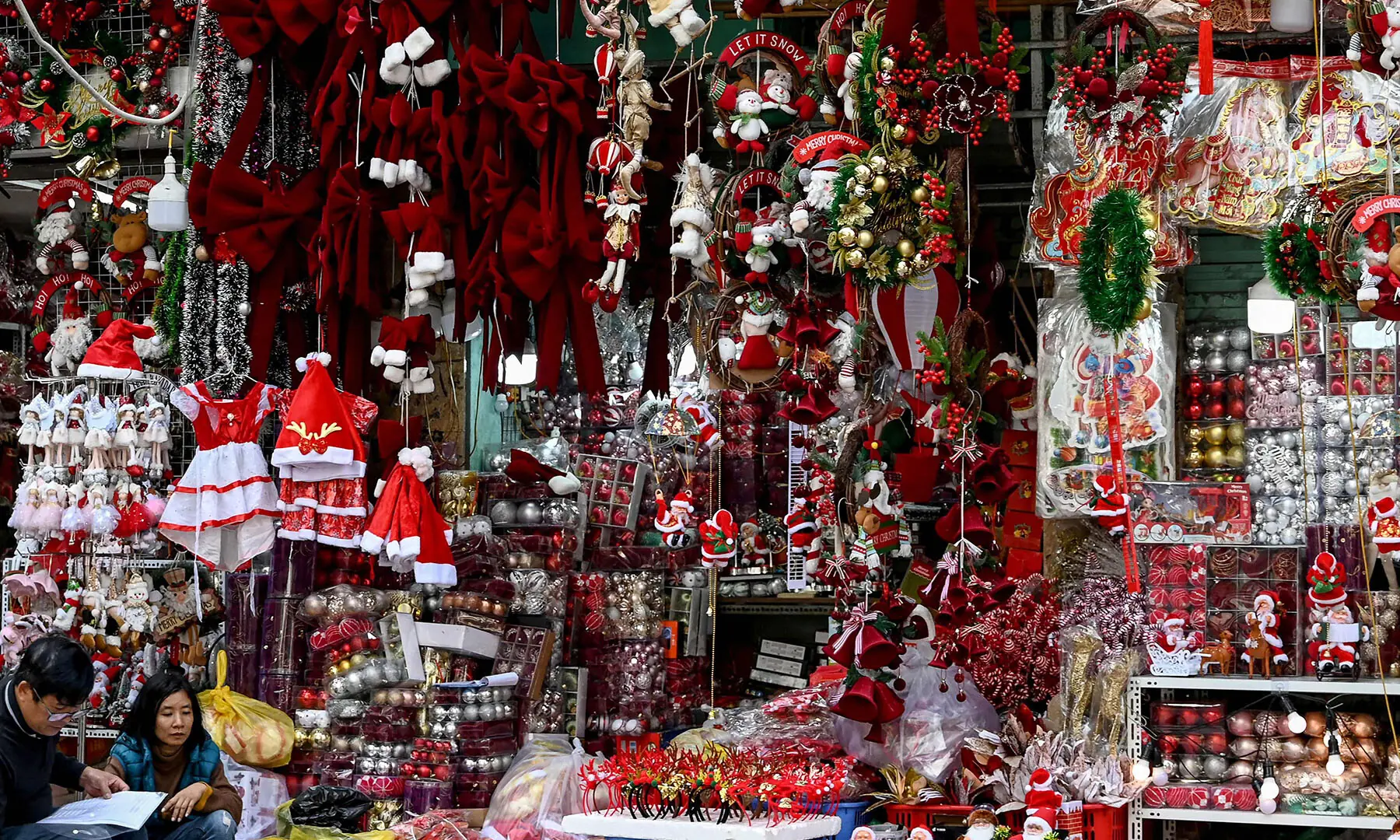 Vendors sit in front of their shop selling Christmas decorations in Hanoi, Vietnam on December 24. &mdash; AFP