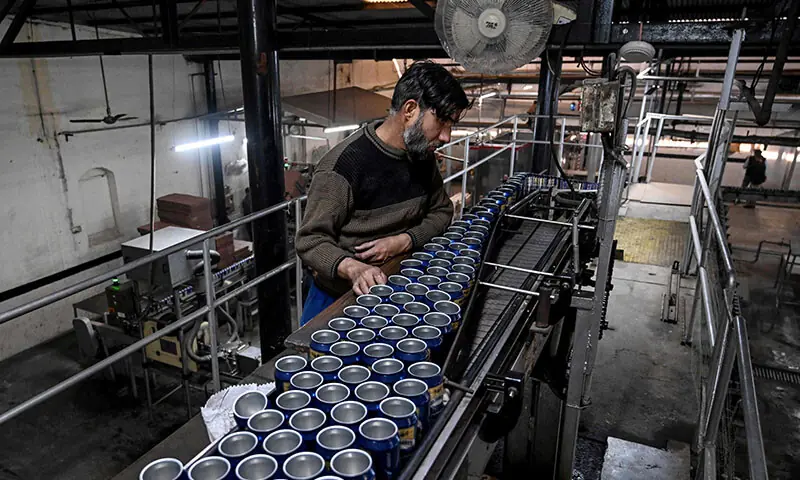 This photograph taken on December 17 shows a worker checking beer cans on a production line at Murree Brewery in Rawalpindi. — AFP