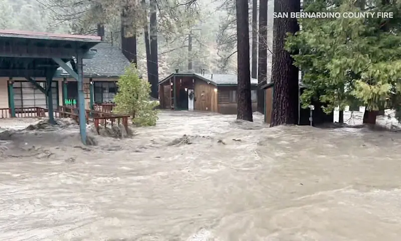 Flood waters flow as houses and trees remain partially submerged after torrential rains in San Bernardino County, California, the US on December 24. — Reuters