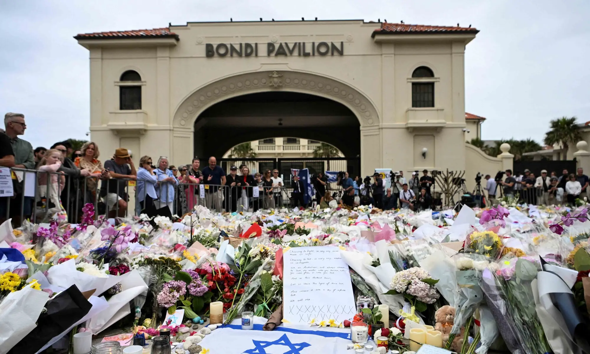 People stand near flowers laid as a tribute at Bondi Beach to honour the victims of a mass shooting that targeted a Hanukkah celebration at Bondi Beach on Sunday, in Sydney, Australia, December 16, 2025. &mdash; Reuters