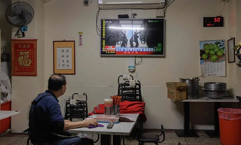 A man watches TV news coverage of the Chinese People’s Liberation Army (PLA) military drills around Taiwan in Keelung, Taiwan on December 30. — AFP