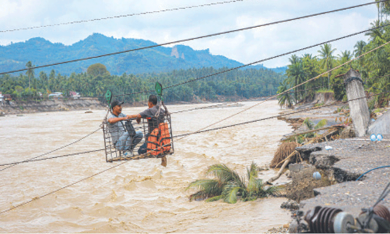Villagers use a makeshift cable car to cross the river after the bridge was destroyed by a flash flood in Indonesia&rsquo;s Bireuen town.&mdash;AFP