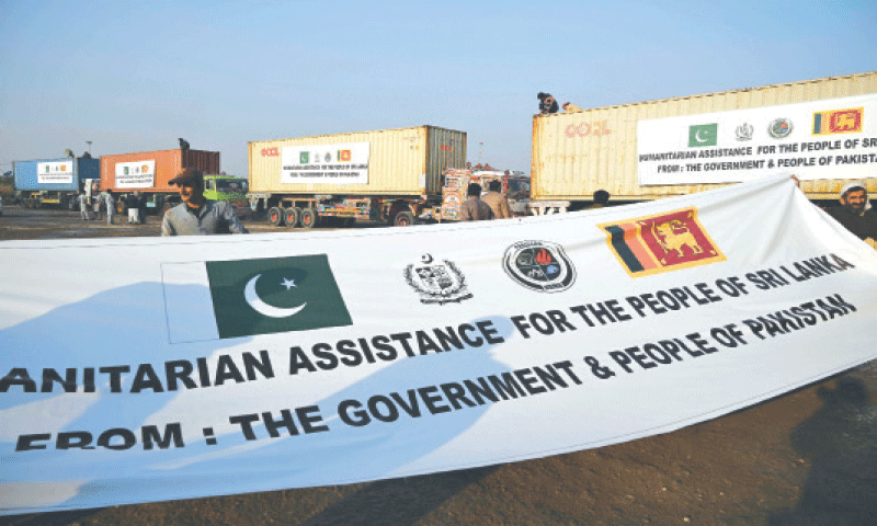 ISLAMABAD: Workers place banners on containers loaded with essential commodities for Sri Lanka&rsquo;s 
flood-affected people.&mdash;AFP
