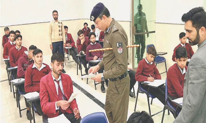 DPO Tariq Aziz Sindhu distributes pamphlets on road safety among students of Government Graduate College Jhelum during an awareness campaign launched in educational institutions of the district on Saturday. - Dawn