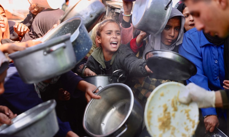 KHAN YUNIS: Displaced Palestinians clamour to receive food handouts at a charity kitchen in the southern Gaza Strip.—AFP KHAN YUNIS: Displaced Palestinians clamour to receive food handouts at a charity kitchen in the southern Gaza Strip.—AFP