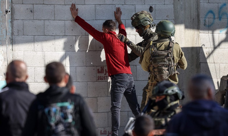 Occupied West Bank: Israeli soldiers frisk a Palestinian youth as residents from the Nur Shams refugee camp return to their homes to retrieve belongings, ahead of the Israeli military’s planned demolition of residential buildings in the camp near Tulkarem.—AFP
