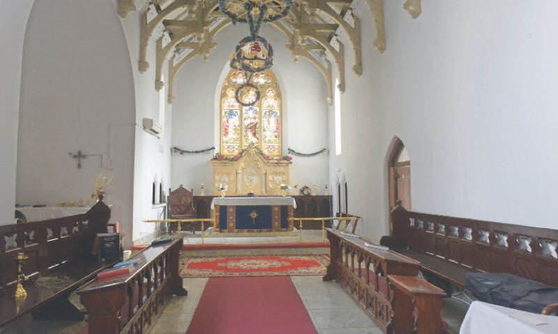 The chancel of the church with stained-glass windows and benches for the clergy.