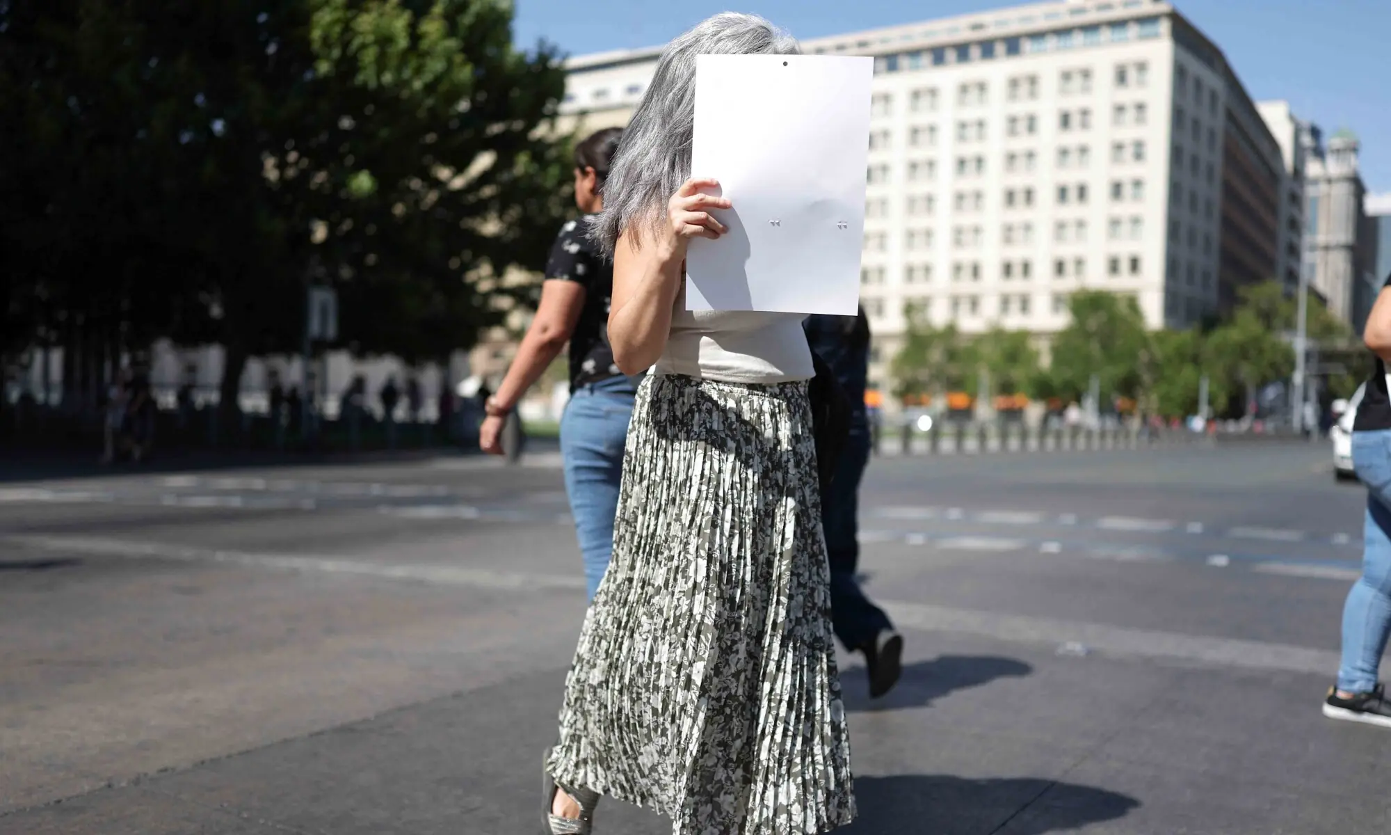 A woman shields herself from the sun with a sheet of paper, during a heat wave in Santiago, Chile, December 30, 2025. &mdash; Reuters