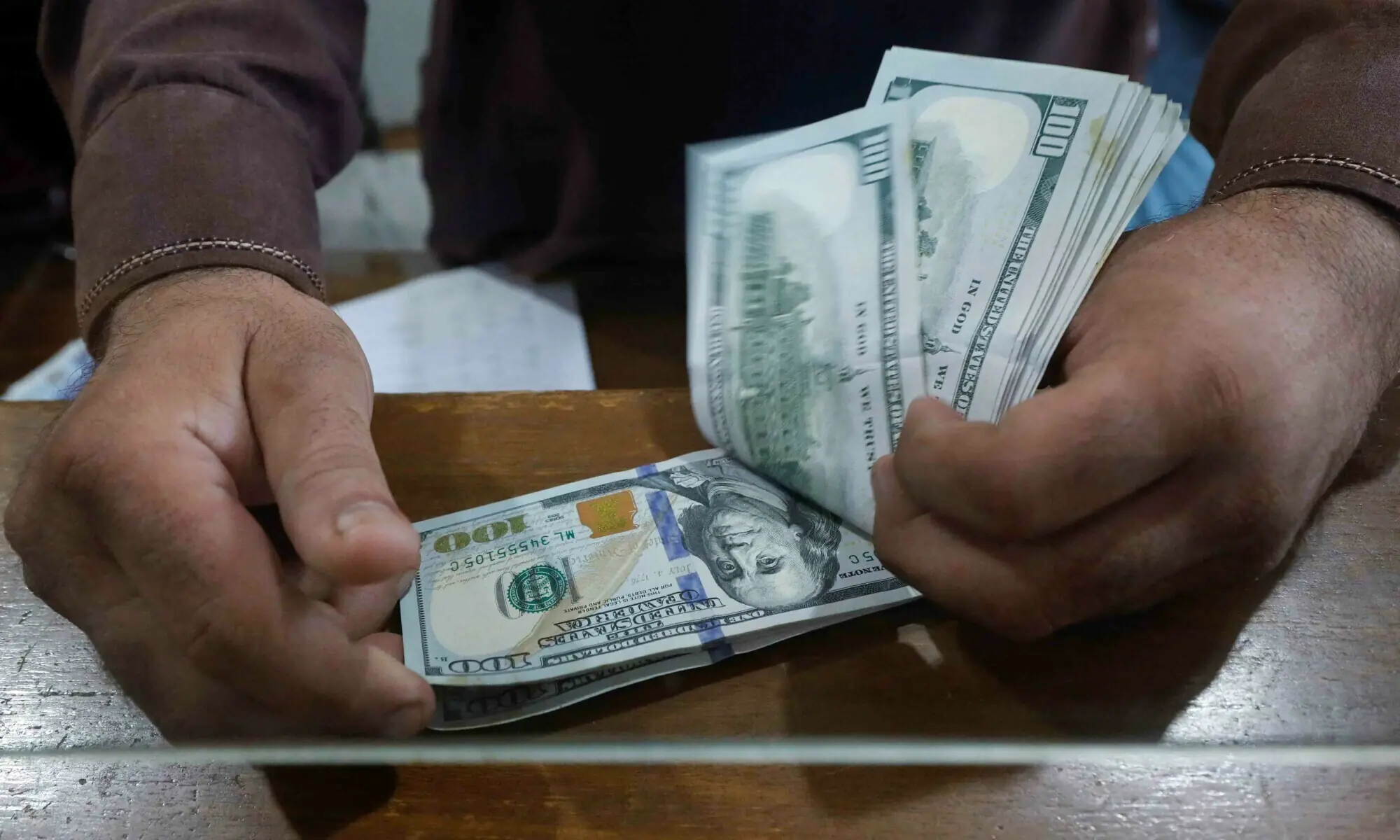 An employee of a foreign exchange shop counts US dollar banknotes from behind a glass booth in Karachi on September 7, 2023. — Reuters/File An employee of a foreign exchange shop counts US dollar banknotes from behind a glass booth in Karachi on September 7, 2023. — Reuters/File