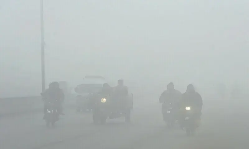 Lahore motorists make their way along a street amid heavy fog. &mdash; AFP/File