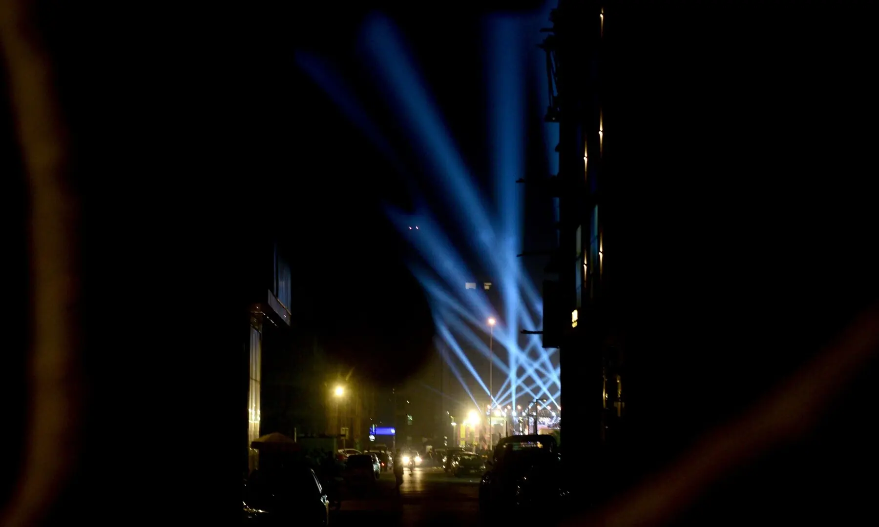 Blue lights emerge from the entrance of the food street, seen through a distant alley. Usually quiet at night, the commercial lane comes alive with the vibrant presence of the food street. &mdash; Tahir Jamal/White Star