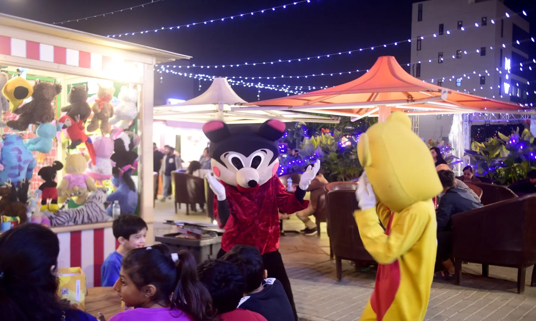 Mascots entertain children at the food street, with a soft toy shop in the background; the street offers not just food but also toys, jewellery, and handicrafts. &mdash; Tahir Jamal/White Star