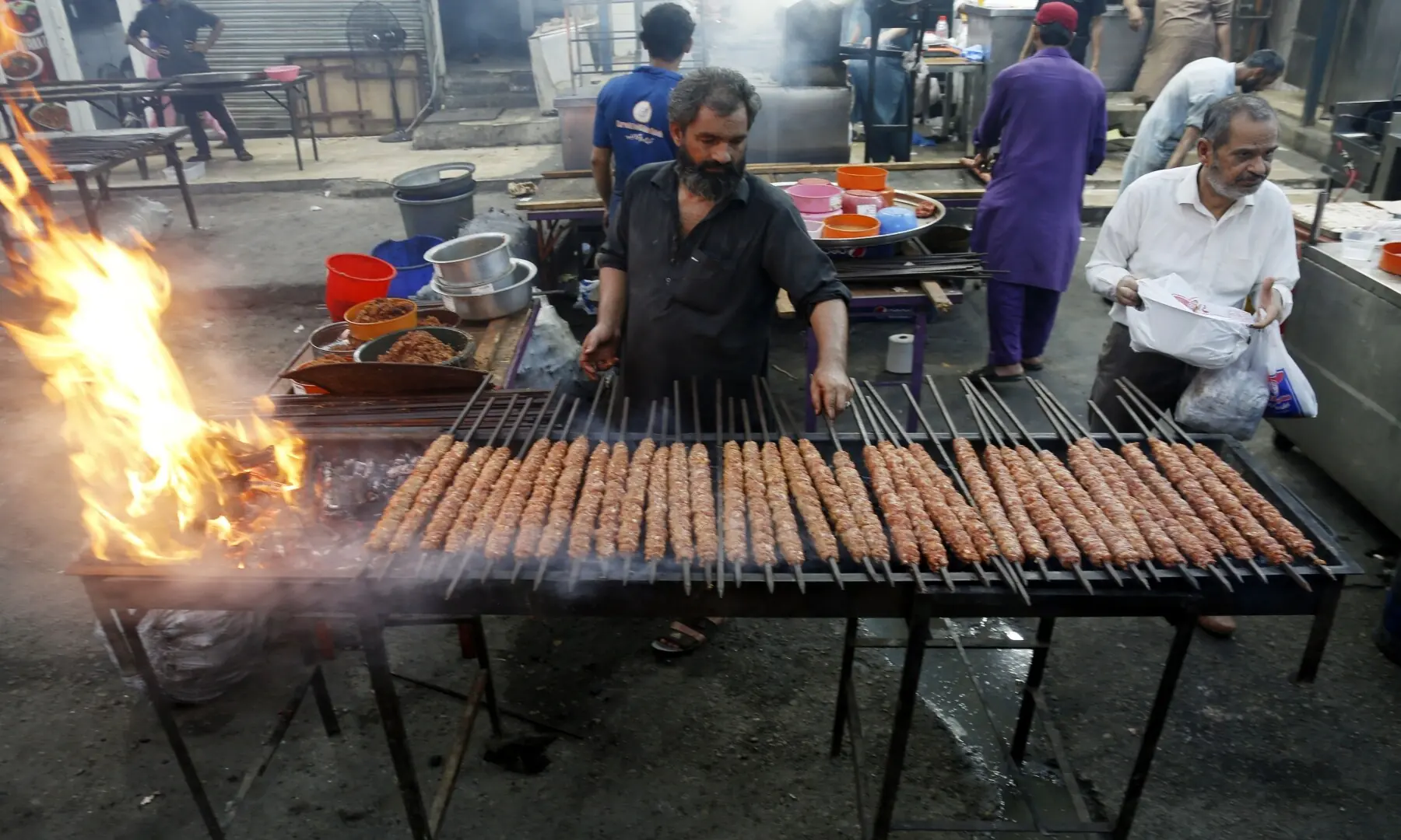 A vendor grills seekh kababs at Burns Road Food Street, spiced minced meat cooked to perfection, drawing food enthusiasts who visit to enjoy hot, flavourful late-night treats. &mdash; Shakil Adil/White Star