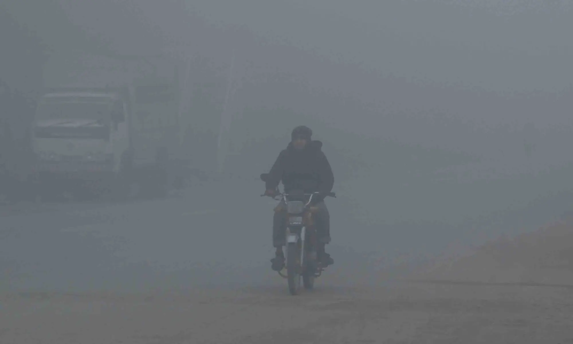 A motorist rides his bike amid dense fog on a winter morning in Islamabad on January 6, 2026. &mdash; AFP