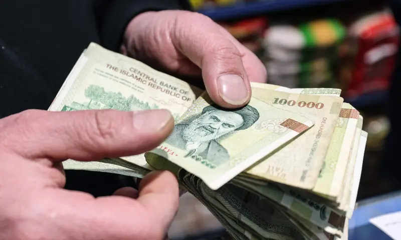 A shop owner counts Iranian banknotes at a store in the capital Tehran on Jan 7, 2026. &mdash; AFP