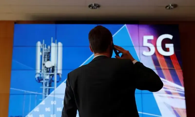 An employee of Germany&rsquo;s Federal Network Agency (Bundesnetzagentur) uses his mobile phone in front of a screen set up for the auction of spectrum for 5G services at the Bundesnetzagentur headquarters in Mainz, Germany, March 18, 2019. &mdash; Reuters
