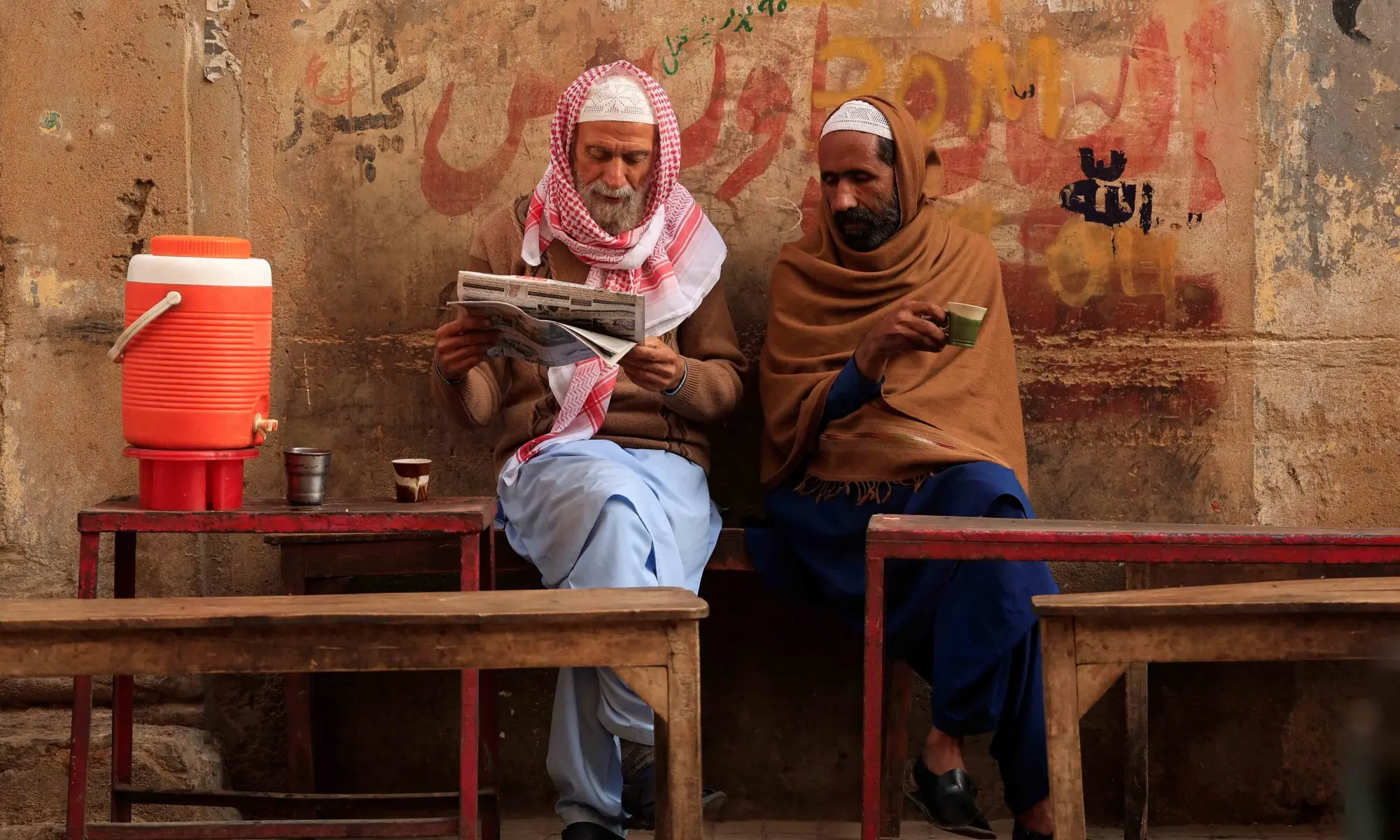 Labourers read a newspaper as they drink morning tea at a stall on a cold winter morning in Karachi, Pakistan, January 2, 2026. &mdash; Reuters