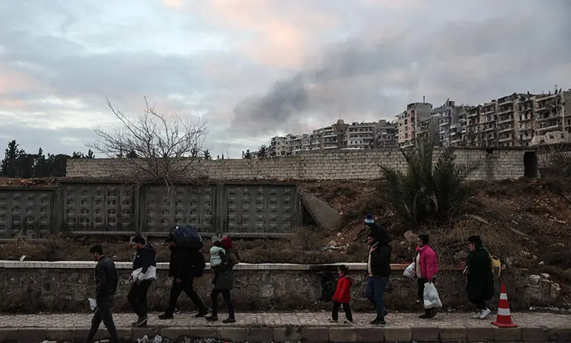 Residents carrying their belongings leave Aleppo’s Kurdish-majority Sheikh Maqsud neighbourhood on January 10, 2026, after days of deadly clashes between Kurdish fighters and security forces. Syrian authorities on January 10 began transferring Kurdish fighters from Aleppo’s Sheikh Maqsud neighbourhood to the country’s northeast, state television reported. (Photo by OMAR HAJ KADOUR / AFP)