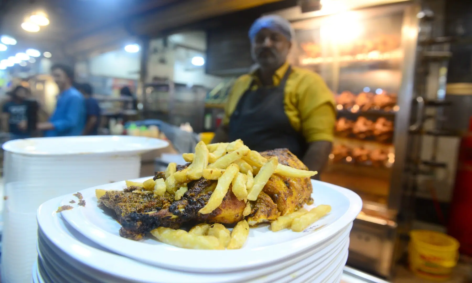 A vendor serves a platter of fries and tikka at his outlet in Hussainabad, combining spicy, grilled flavours with crispy street snacks. &mdash; Tahir Jamal/White Star